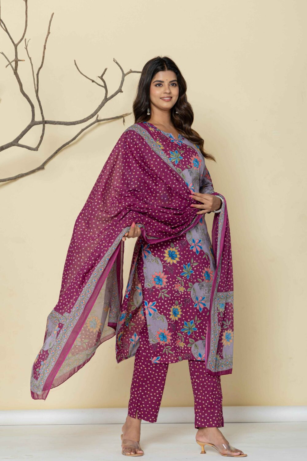 Woman wearing a purple floral printed kurti pant dupatta set with dot design.
