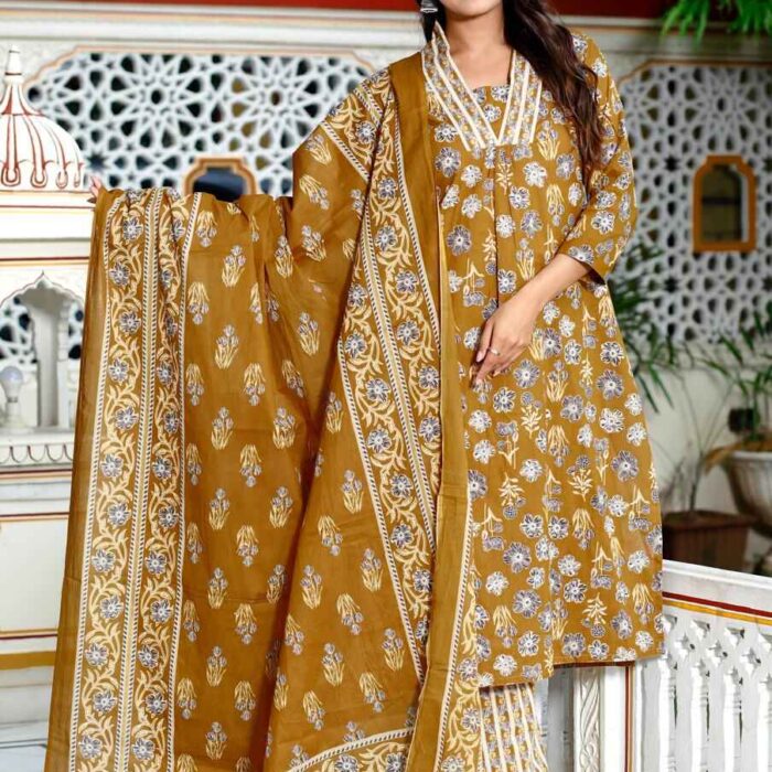 Woman wearing HK Vastra mustard yellow cotton suit set with white floral block print, lace neckline detail, and matching dupatta standing in a heritage background."
